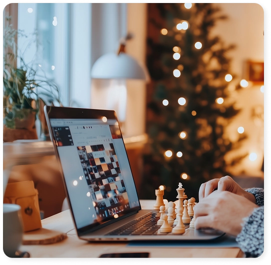 Een man speelt thuis schaak op zijn laptop, in een gezellige omgeving met de schaakstukken naast zich